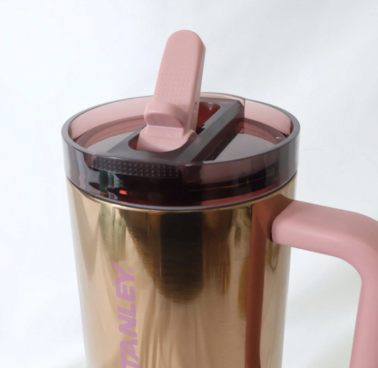Stanley bronze tumbler close-up with pink handle and flip lid